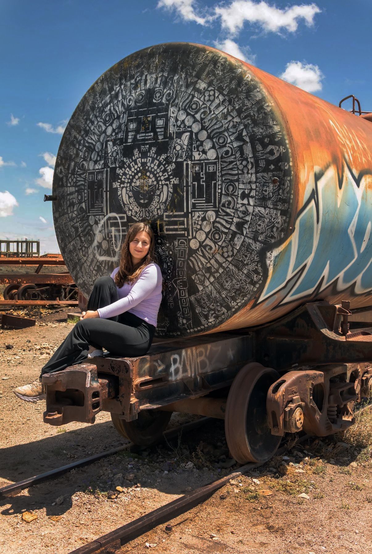 Sofia sitting on a graffiti-painted rail tanker in Bolivia